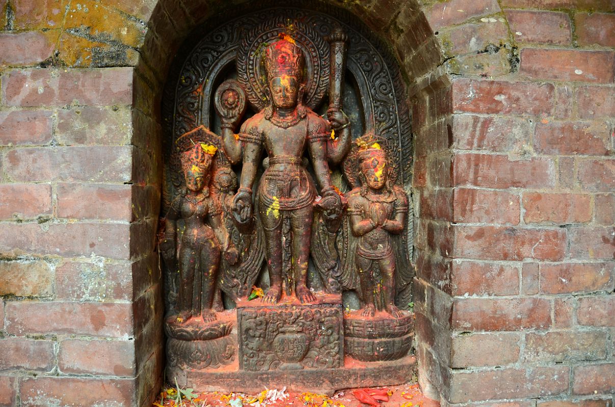 Kathmandu Changu Narayan 25 Sridhar Vishnu With Lakshmi And Garuda Just To The North Of Main Entrance To Changu Narayan Temple Sridhar Vishnu stands on a pedestal holding a chakra wheel and lotus in his right hands, and a small mace club and conch shell in his left hands just to the north of the main entrance to Changu Narayan Temple in the Kathmandu Valley. The other two figures are Lakshmi (Laxmi) and Garuda. This image dates from around the ninth century.